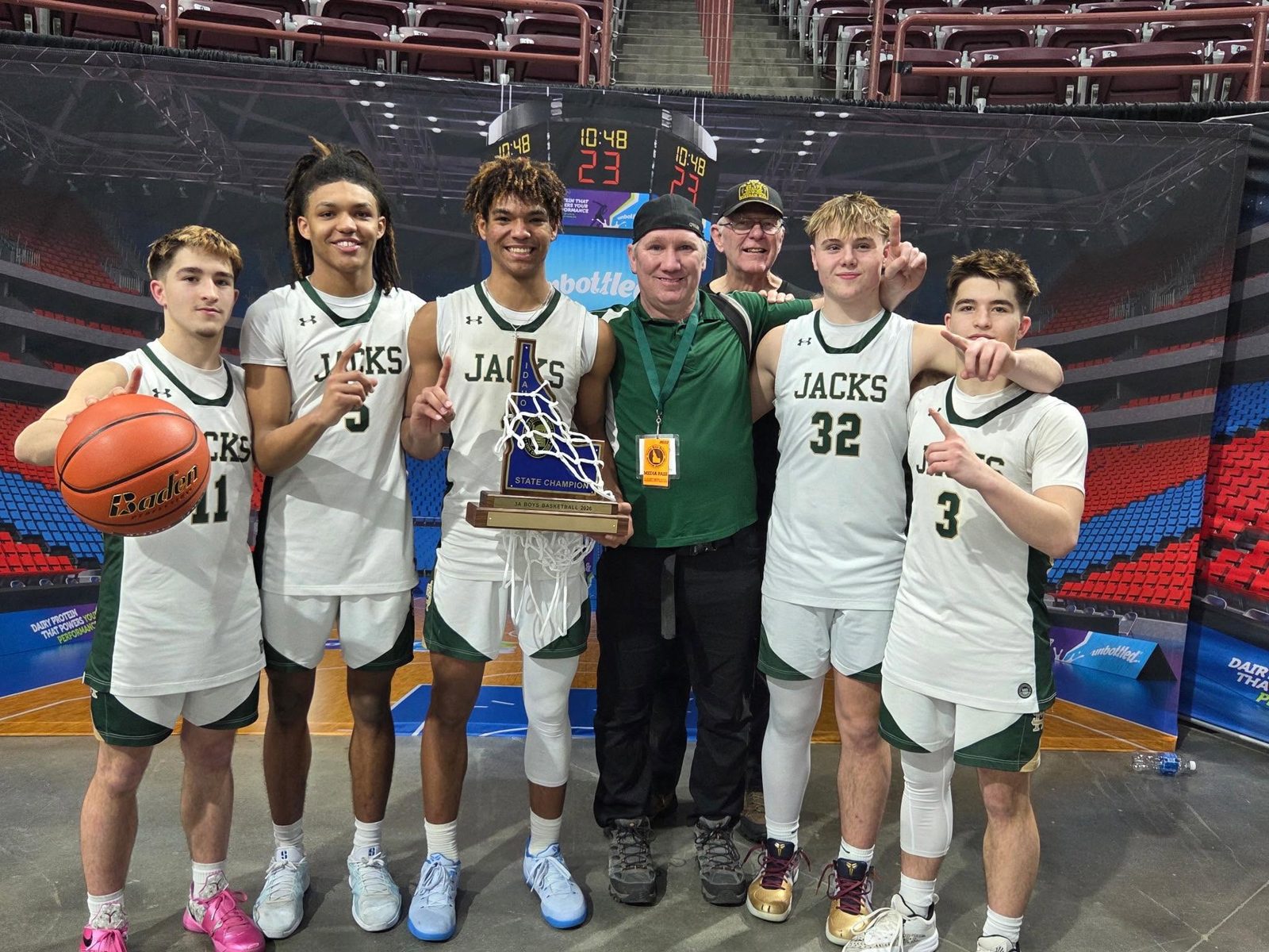 St. Maries Lumberjacks basketball players holding a trophy with the KOFE broadcaster